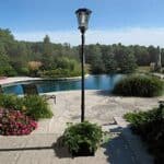 Shows the sun-ray abigail solar lamp post planter model setup in a yard with a pool - techgoodandbad.com 